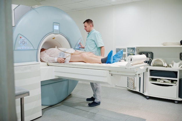 male doctor turns on magnetic resonance imaging machine with patient inside