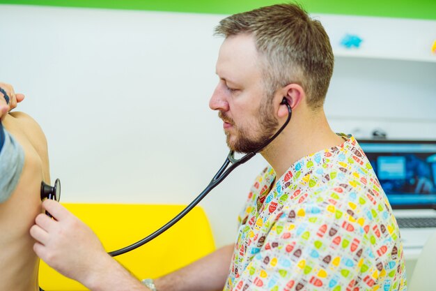 Foto medico maschio utilizzando uno stetoscopio per esaminare il ragazzino