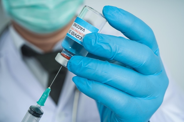 Male Doctor wearing PPE with a stethoscope on shoulder and holding syringe COVID19 vaccine CORONA vaccine concept Healthcare and Medical