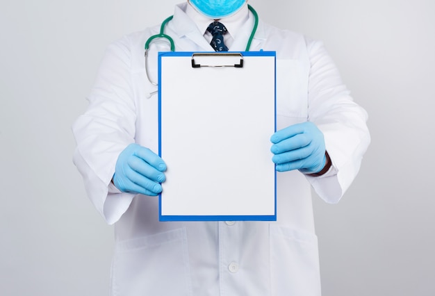 Мужской доктор в белом халате, синие латексные перчатки, на шее висит стетоскоп, доктор держит держатель для бумаги