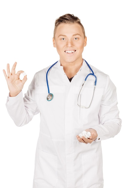 白い丸薬を示す白いコートの手で男性医師人と薬の概念白い背景で隔離の画像