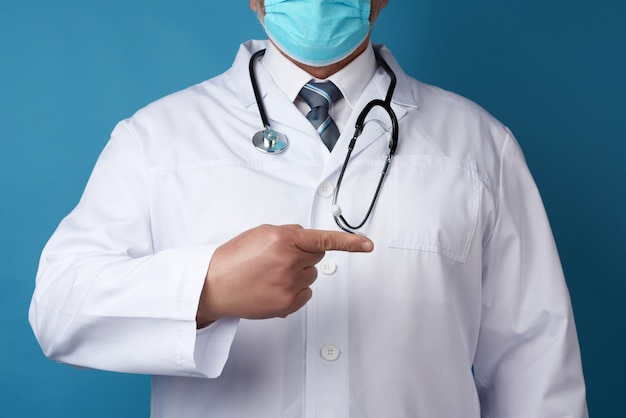 Male doctor in a white medical coat stands on a blue background