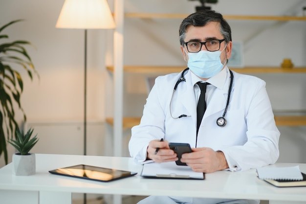 Male doctor with medical face mask and a stethoscope at clinic