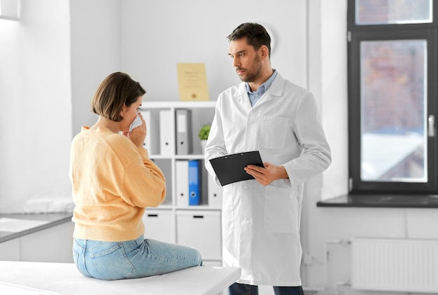 male doctor and woman blowing nose at hospital