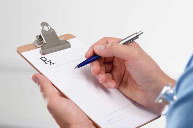 Male doctor writing prescription on clipboard