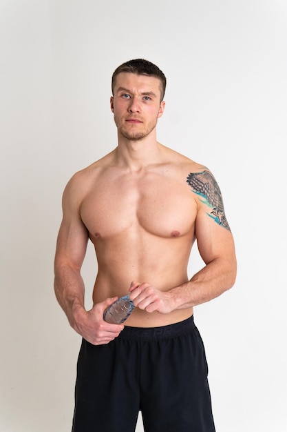 Acqua potabile maschile fitness viene pompato con un asciugamano su uno sfondo bianco isolato fitness atleta bere maschio adulto tenendo pausa asciugamano copia ritmo caucasico un muscolo
