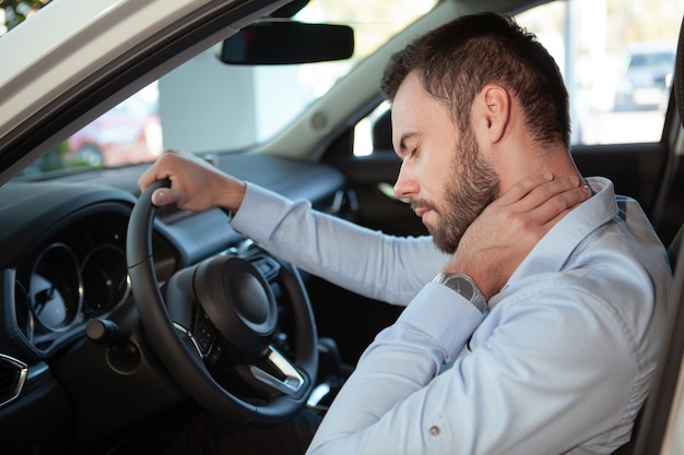 Male driver having neck pain, sitting in his car