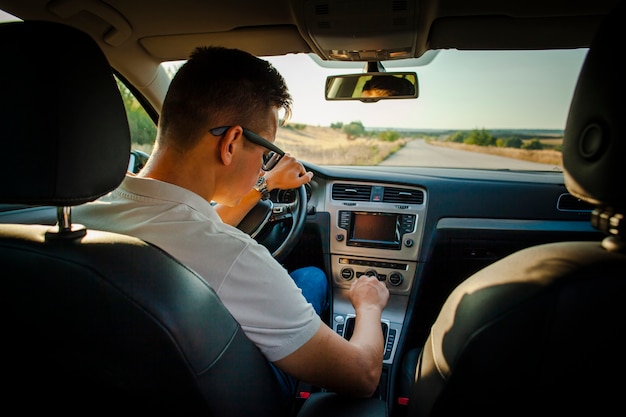 Photo male driver holding wheel and adjusting radio