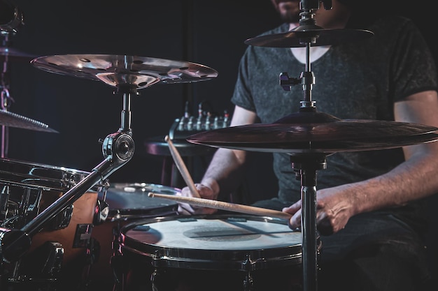 A male drummer plays the drums in a dark room