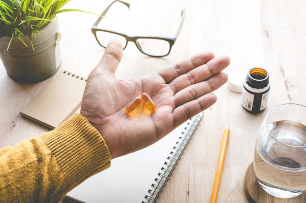 Maschio che mangia medicina, pillola (vitamina) sul lavoro al mattino. idee di concetti di stile di vita sano