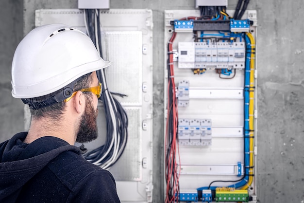 Un elettricista maschio lavora in un quadro elettrico con un cavo di collegamento elettrico