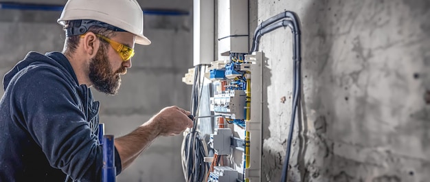 Photo a male electrician works in a switchboard with an electrical connecting cable