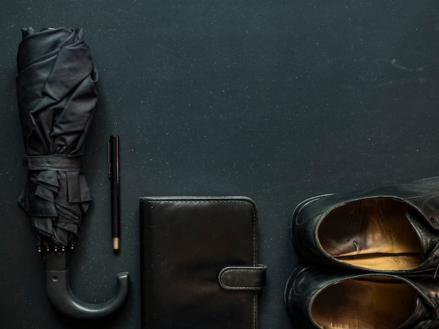 Мужской элегантный модный бизнесмен поставляет зонтик обувь блокнот и ручка копией пространства