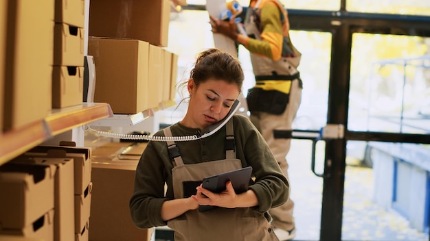 Photo male employee answering phone in depot, discussing about supply chain and distribution with products. young person inspecting merchandise before order shipment, quality control. handheld shot.