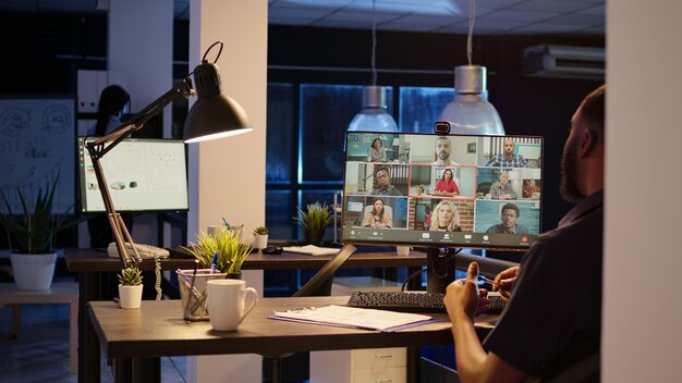 Male employee attending business meeting on teleconference,\
chatting with colleagues on online videocall conference. using\
computer with webcam to talk on remote videoconference call.