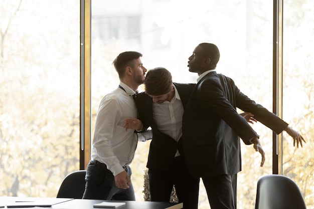 写真 男性従業員が離れて怒って攻撃的な多様な同僚がオフィスで喧嘩を戦う