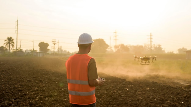 Un ingegnere maschio che controlla il drone che spruzza fertilizzanti e pesticidi su terreni agricoli