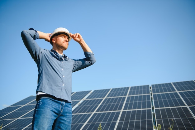 Male engineer in a helmet standing near the solar panels looking up Green ecological power energy generation Solar station development concept Home construction