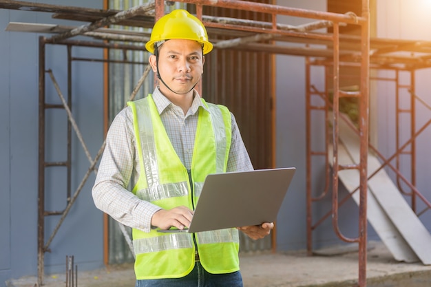 A male engineer looks at the floor plan at the construction site.