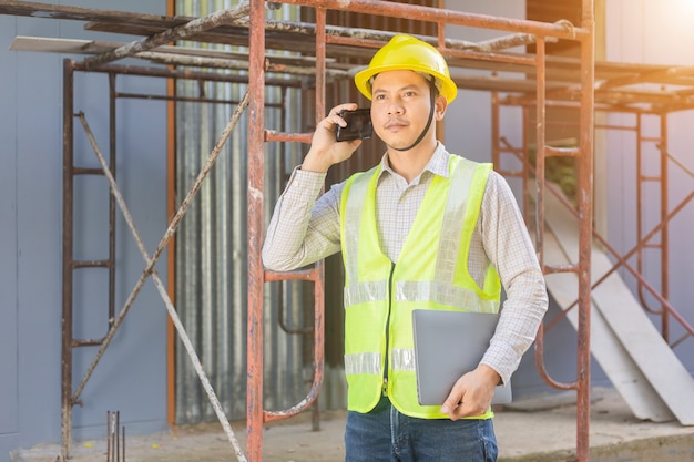 A male engineer looks at the floor plan at the construction site.