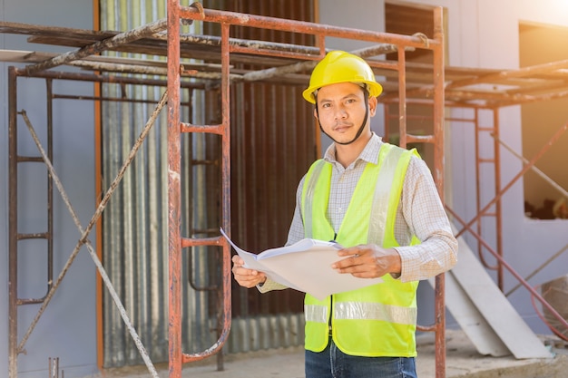 A male engineer looks at the floor plan at the construction site.