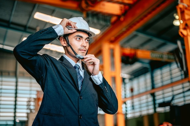 Photo the male engineer manager was wearing a safety helmet before inspecting the machines