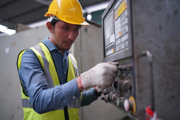 Male engineer metalworker industrial experienced operator technician worker in safety hard helmet working on lathe machine, professional man in industry technology manufacturing factory workshop