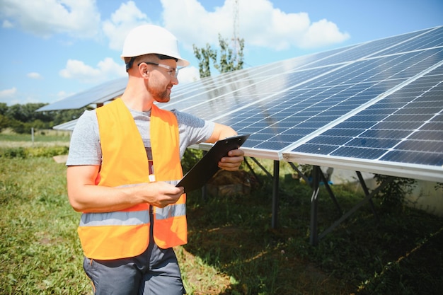 Мужчина-инженер в защитном шлеме устанавливает систему солнечных фотоэлектрических панелей. Альтернативная энергетическая экологическая концепция.