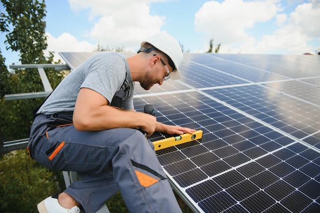 Male engineer in protective helmet installing solar photovoltaic panel system Alternative energy ecological concept