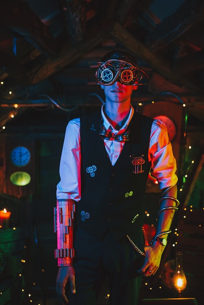 Male engineer in a steampunk suit with mechanisms and glasses in a fabulous post-apocalyptic atmosphere