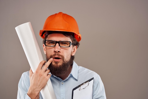 Male engineer with glasses in orange paint Professional blueprints in hands High quality photo