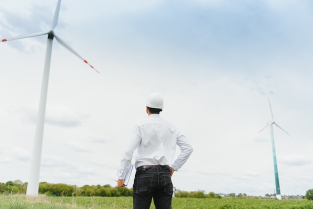 Male engineer with hard hat working at the wind turbine farm