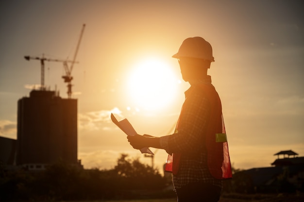 Foto ingegnere maschio che lavora in cantiere all'ora di silhouette sunset