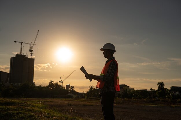 Ingegnere maschio che lavora in cantiere all'ora di silhouette sunset