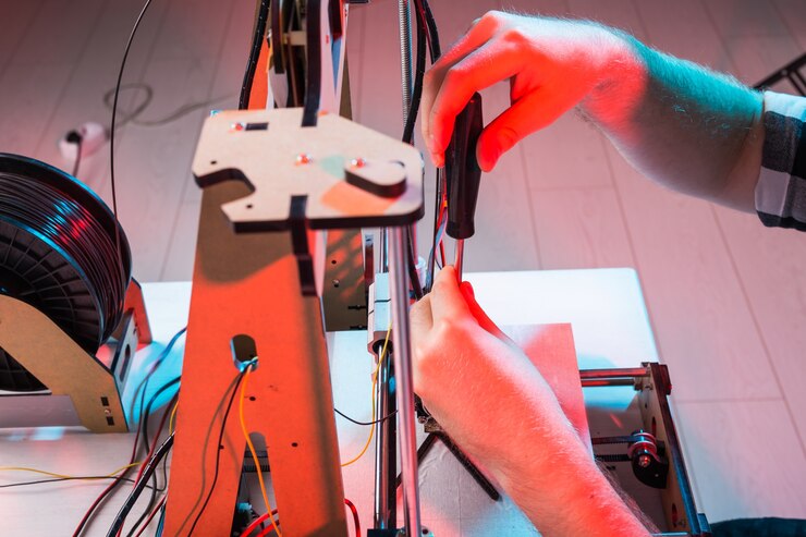 Photo male engineer working at night in the lab, he is adjusting a printer components.