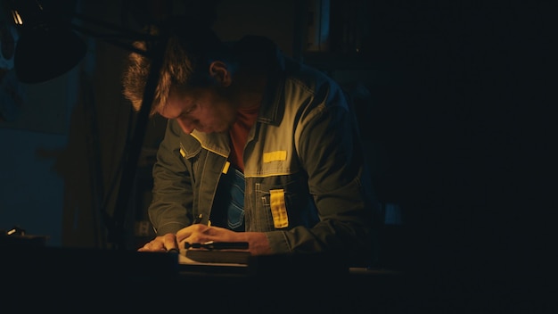 A male engineer works with drawings lying on the table using a pencil