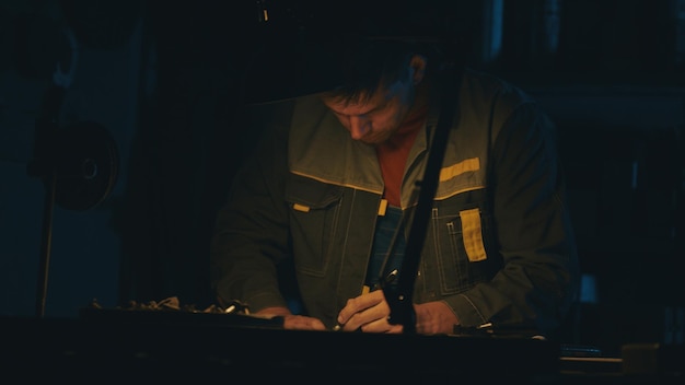 A male engineer works with drawings lying on the table using a pencil