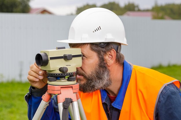 Foto un ingegnere maschio lavora con il livello ottico sul sito