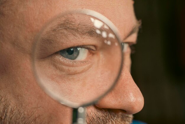 Male eye through a magnifying glass closeup