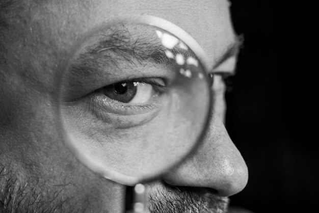 Male eye through a magnifying glass closeup