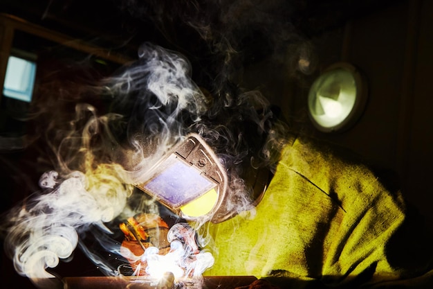 Male in face mask welds with welding