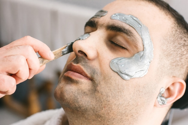 Male face waxing. Barber removes hair by shugaring from the face of turkish man.