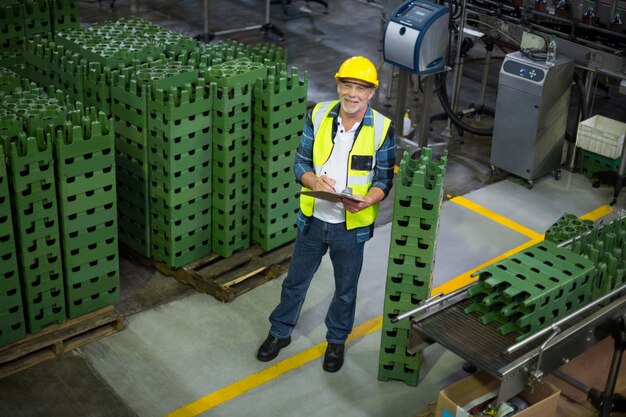 Male factory worker maintaining record on clipboard