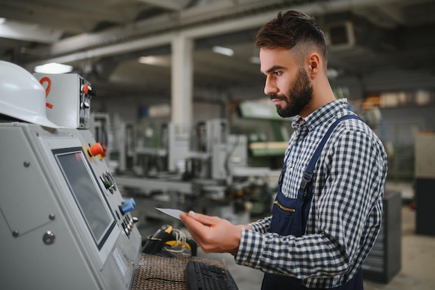 Male factory worker working or maintenance with the machine in the industrial factory while wearing safety uniform and hard hat