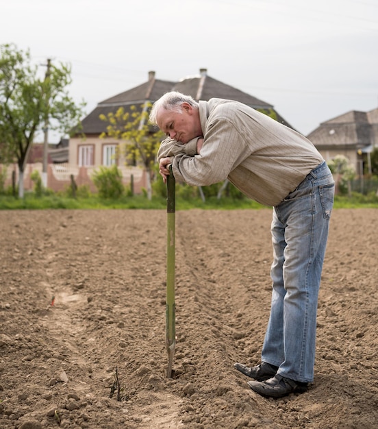 Foto agricoltore maschio che scava nel giardino