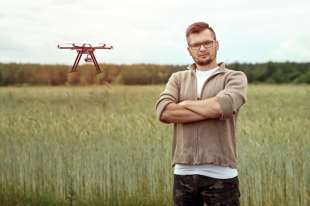 A male farmer manages a drone over agricultural land.