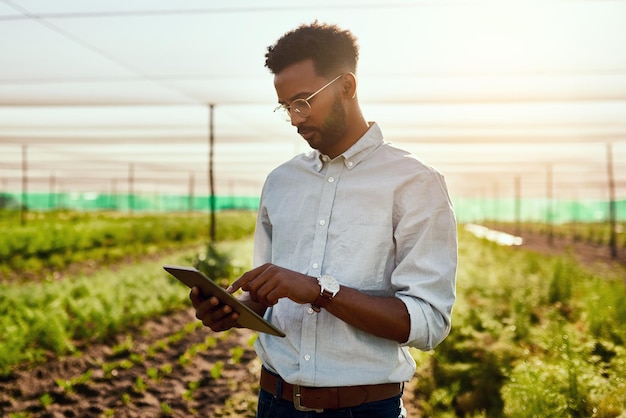 Male farmer planning online strategy on a tablet looking at farm growth outdoors Digital agriculture analyst analyzing farming data Worker research environment and sustainability