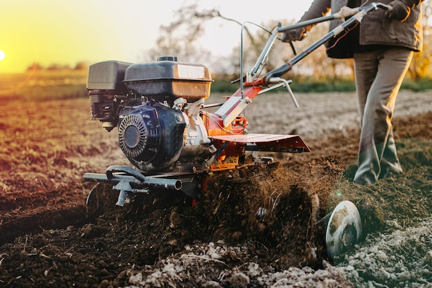 male farmer plows the land with a walkbehind tractor in the village home agriculture