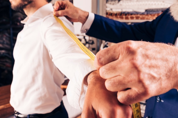 Male fashion designer's taking measurement of sleeves in the workshop