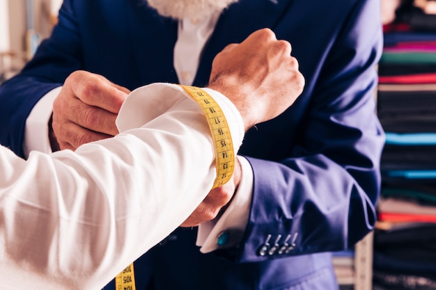 Photo a male fashion designer taking measurement of his customer's cufflink